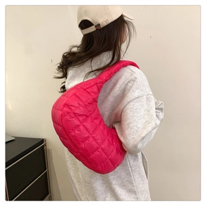 Rear view of a pink quilted puffer bag on model showing diamond stitching and shoulder fit