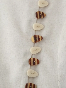 Detailed macro view of asymmetric pebble buttons on linen blend fabric texture