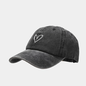 Close-up of white heart embroidery on washed cotton baseball cap with vintage texture