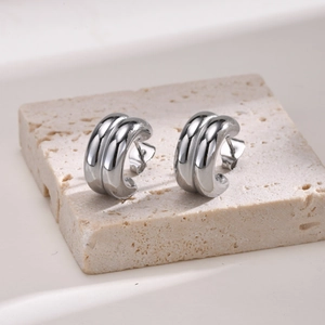 Macro view of silver double C-shaped earrings on textured stone base in high polish