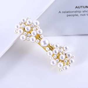 Close-up of golden hair clip decorated with elegant white faux pearls on a white background
