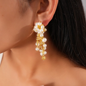 Detail of gold flower earrings with white pearls and sparkling rhinestones on model