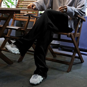 Detailed texture of black pleated fabric on men's relaxed fit trousers outdoors