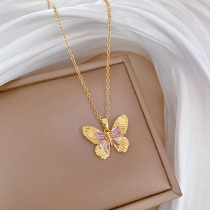 Detailed macro view of a gold-toned butterfly pendant with purple cubic zirconia crystals