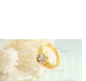 Detailed macro of a gold-plated ring with round clear crystal on white coral background