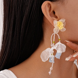 Close-up of long tassel earrings with lace flowers and blue fringe on a model