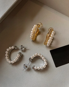 Macro shot of silver needle C-shaped earrings with pearls and pavé cubic zirconia details