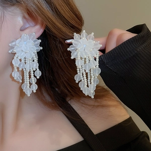 Detail of long white acrylic pearl tassel earrings showing the elegant dangling cluster design
