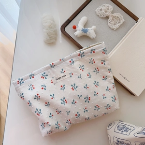 Close-up of cotton floral makeup bag with cherry prints and textured canvas fabric