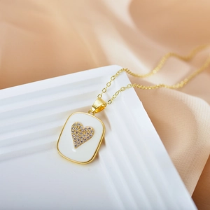 Close-up of golden heart pendant with white enamel and sparkling zircon inlay detail