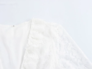 Détails de la broderie en dentelle et du col en V sur une robe longue de vacances blanche