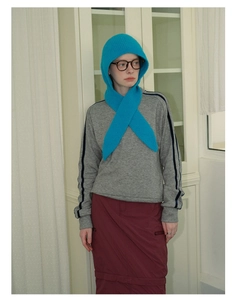 Close-up of a blue knitted hooded scarf paired with a grey striped sweater and glasses