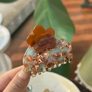 French retro acetate flower hair claw with marble texture and golden logo detail
