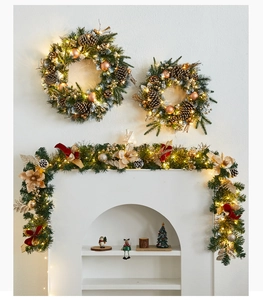 Close-up of Christmas wreath and garland with warm LED lights and red velvet bows