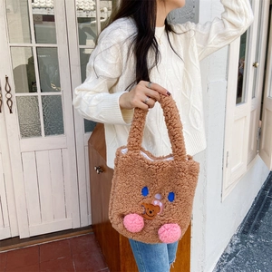 Detailed view of brown plush handbag with cute bear face embroidery and pink pompom cheeks