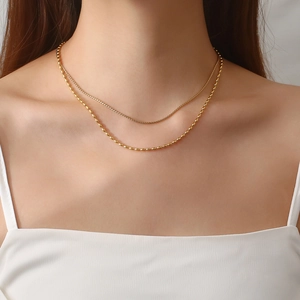 Close-up of double-layered gold bead chain necklace worn on a model's collarbone