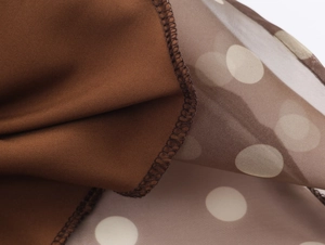 Detail of dark brown polka dot organza fabric texture and high-quality edge stitching