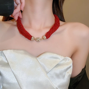 Detail showing red multi-strand seed bead necklace with gold rhinestone sphere