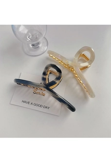 Detail of marble pattern and cream resin hair claws with golden metal spring clips