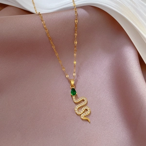 Macro shot of gold snake necklace with green teardrop stone and pavé zircon details