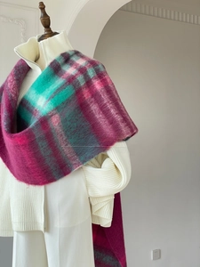 Detail view of colorful plaid thick fuzzy scarf styled over white sweater and trousers