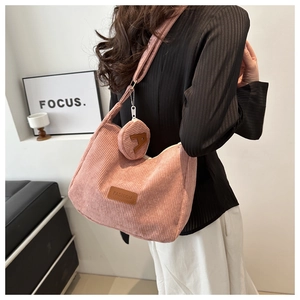 Detail of pink corduroy handbag featuring round coin purse and fashion logo plaque