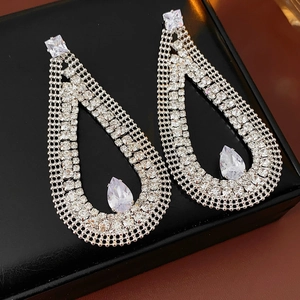 Macro detail of silver-tone teardrop earrings featuring mesh metal and pavé zircon crystals