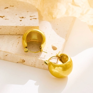 Detailed macro of polished gold twisted rope hoop earrings with brushed metal interior texture