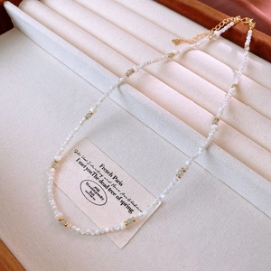 Detail of beaded shell necklace with green stone accents on a velvet tray