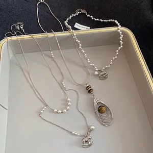 Elegant pearl choker with horse pendant and tiger eye stone necklace on display