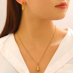 Nahaufnahme von minimalistischem goldenen Tropfen-Halsketten und Ohrring-Set am Modell