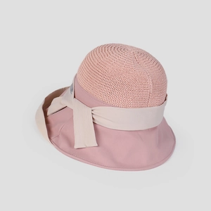 Detail of pink sun hat featuring hollow knit crown and cream bow ribbon decoration