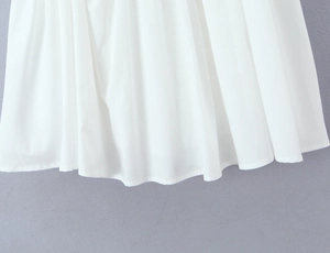 Detailed close-up showing the pleated hem and fabric texture of the white mini dress