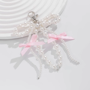 Close-up of pearl bow pendant with hanging pink ribbon bows on a white base