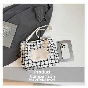 Detail of houndstooth canvas tote bag with front leather pocket and cat charm accessory