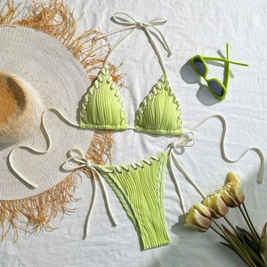 Detailed view of neon green ribbed bikini with white drawstring cut-outs and wavy texture