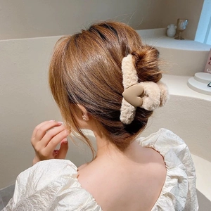 Detail of plush hair claw clip in beige featuring a matte heart on a fuzzy texture
