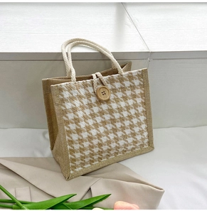 Detail of houndstooth canvas tote bag featuring thick rope handles and wooden button closure