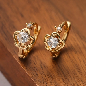 Exquisite gold-plated crown earrings with cubic zirconia stones on dark wood background