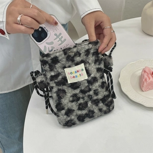 Detail showing phone storage in leopard plush bag with magnetic snap and logo tag