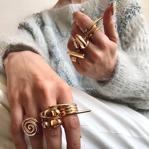 Close-up of chunky gold geometric open rings styled with a soft knit sweater