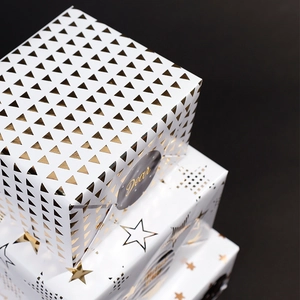White and gold foil gift wrapping paper with star patterns for birthday and holiday gifts