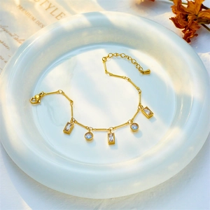 Elegant gold titanium bracelet with geometric square and round crystals on a white plate