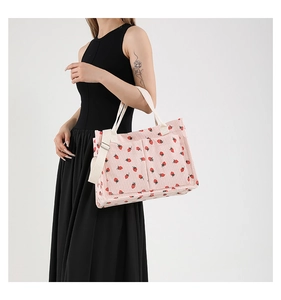 Detailed shot of pink corduroy tote bag with strawberry prints on female model