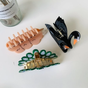 Flat lay of colorful acetate bird hair claws featuring black swan and parrot designs