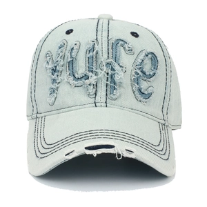 Détail de la casquette de baseball en denim bleu clair avec écusson YUFE et bord usé