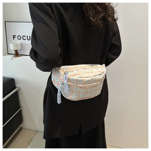 Detailed view of light blue woven chest bag with orange texture on black blazer model