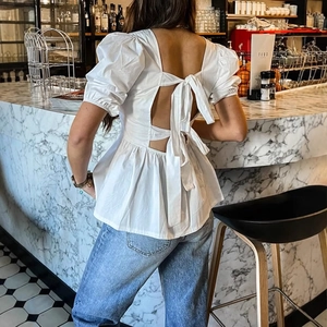 Haut blanc dos nu avec nœud papillon et manches bouffantes sur un jean bleu
