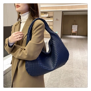 Blue woven leather hobo shoulder bag styled with an elegant khaki suit on a model