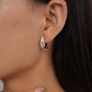 Close-up of metallic silver interlocking hoop earrings on model with high gloss finish